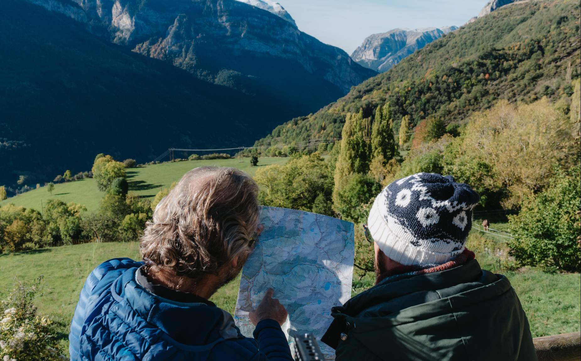 Dos turistas viendo un mapa en un paisaje de bosque y monta&ntilde;as