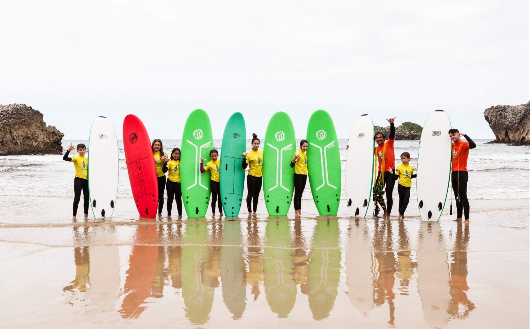 Children and instructors with surfboards on the beach