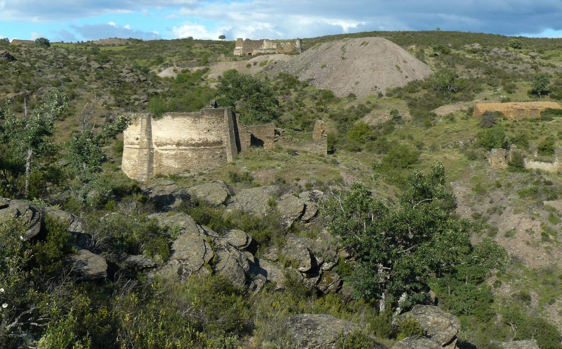 Paisaje de arboles y rocas con edificios antiguos en ruinas