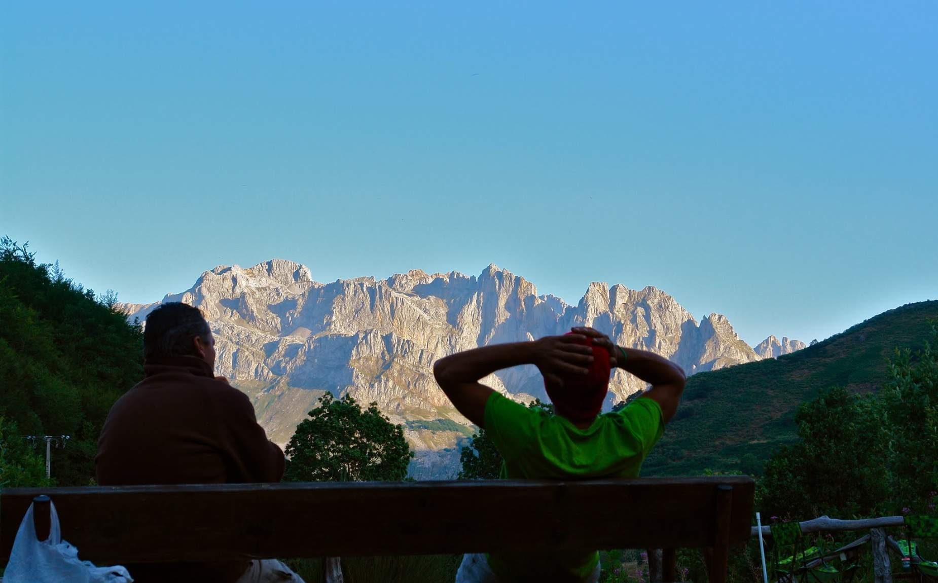 Dos personas sentadas en un banco visualizando el paisaje monta&ntilde;oso
