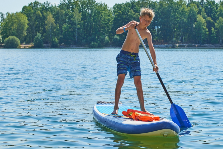 chico haciendo paddle surf en el pantano