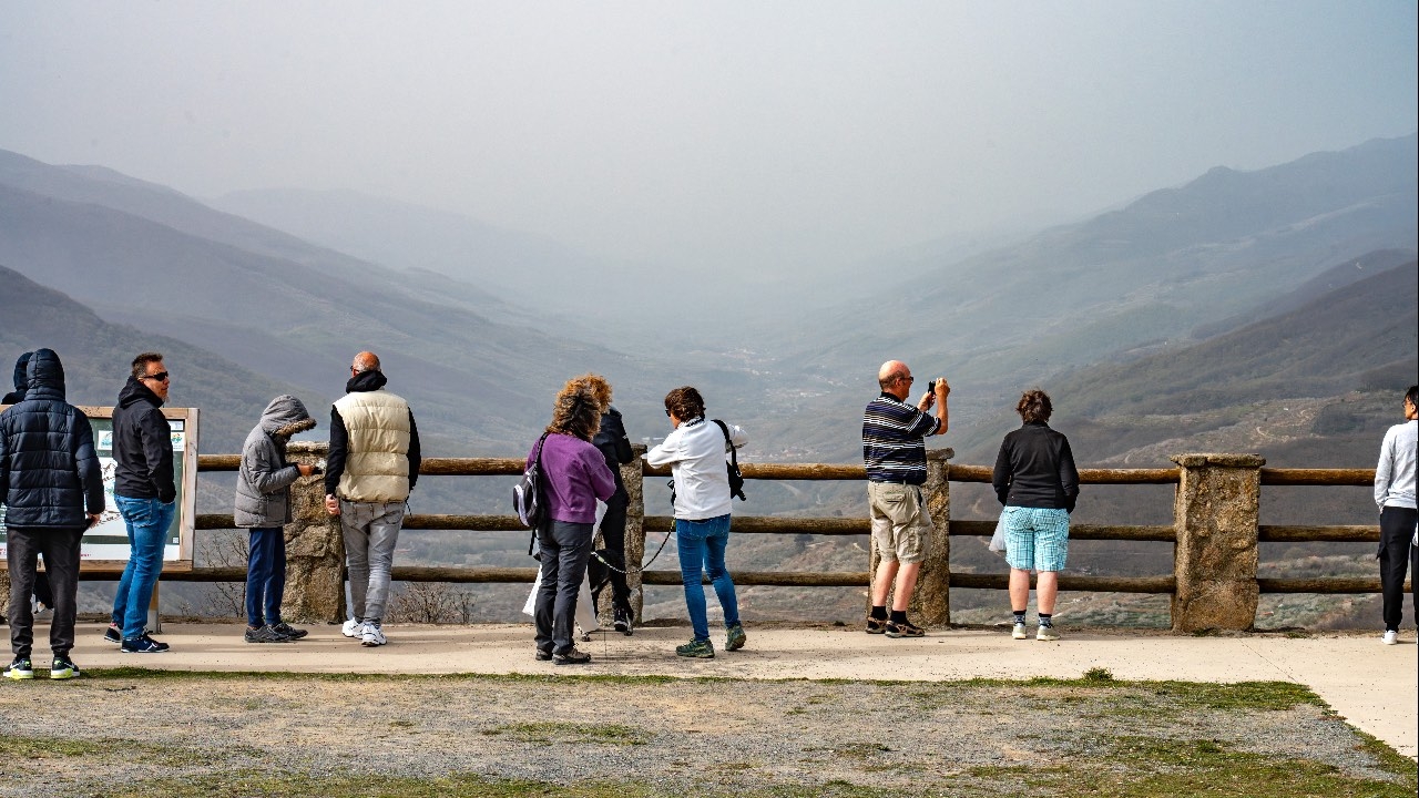 Tourists enjoying the views of the Jerte Valley, shown in the background.