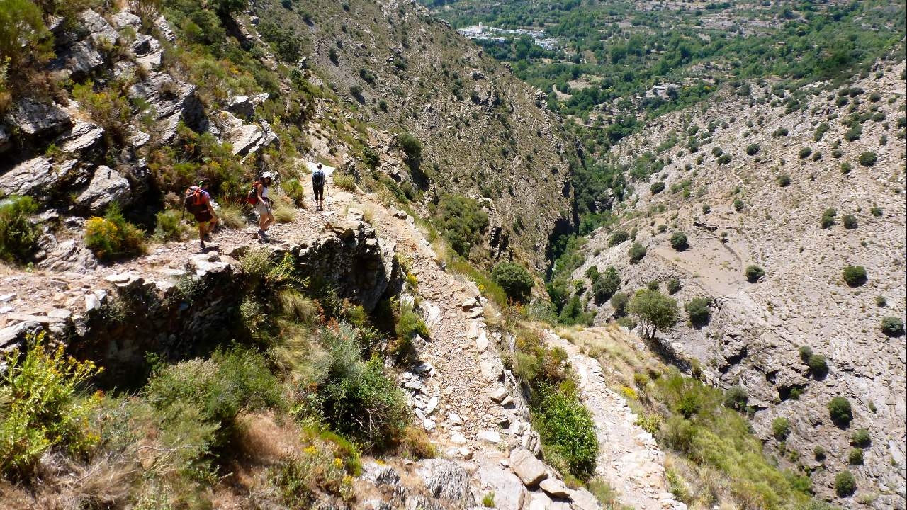 Tourists walking along a rocky trail on a mountainside