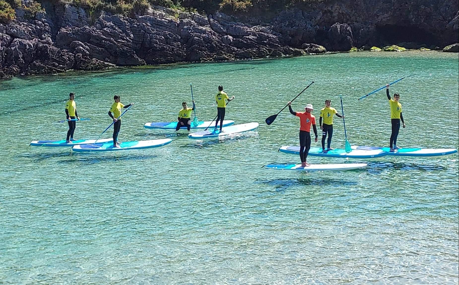 Varias personas con el monitor aprendiendo paddle surf