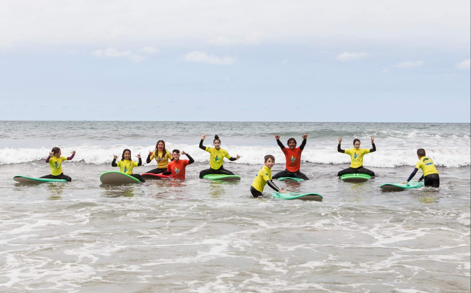 Several children with their instructors enjoying a day of surfing