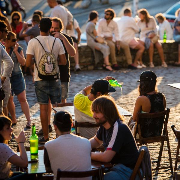 Varias personas sentadas en una terraza de un bar tomando sidra asturiana