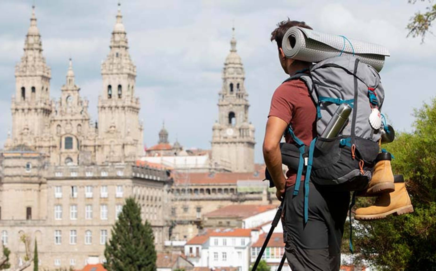 Turista de espaldas con la mochila a cuesta mirando la catedral a lo lejos