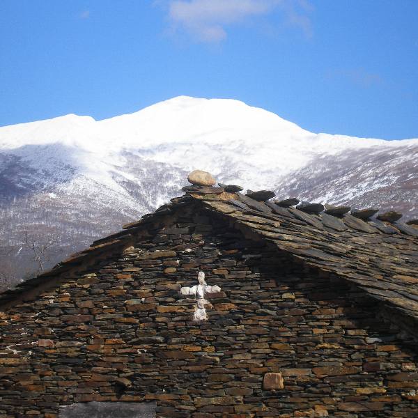 Casa con una cruz y vistas a las montañas nevadas