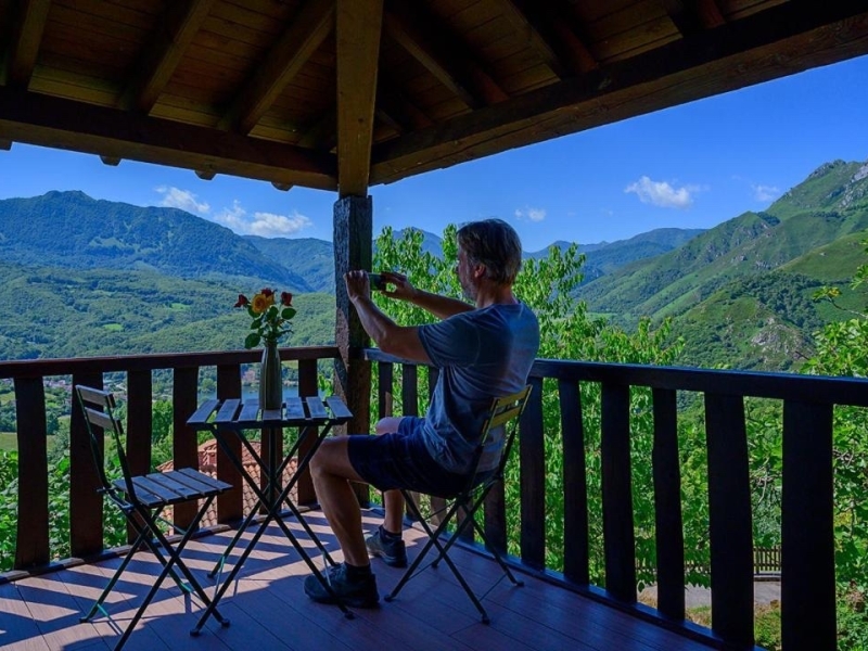 hombre haciendo fotos al paisaje montañoso en el balcón de su habitación
