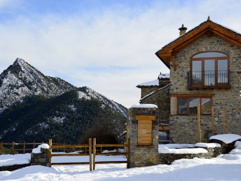 Casa de piedra y madera rodeado de nieve en la montaña