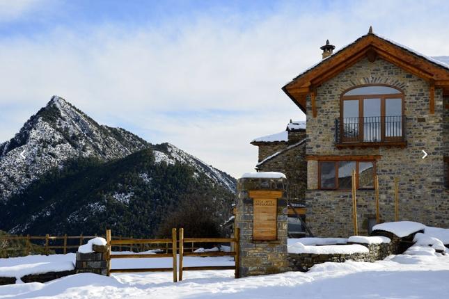 Casa de piedra y madera rodeado de nieve en la monta&ntilde;a